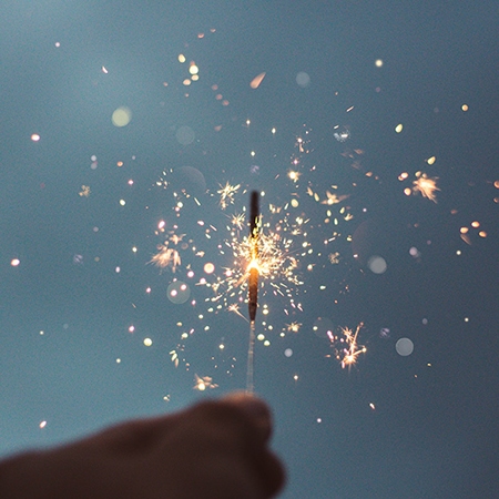 A hand holding a lit sparkler on New Years Eve