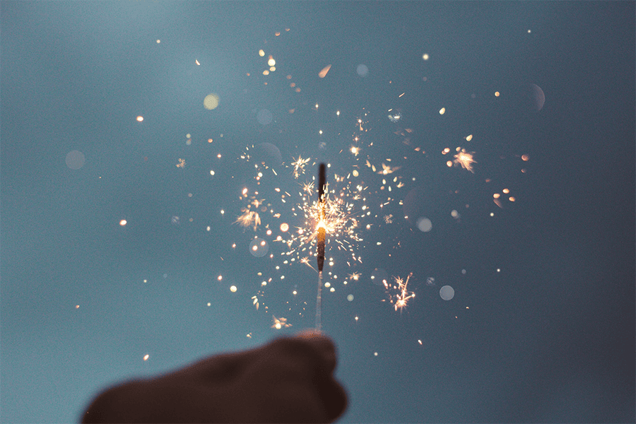 A hand holding a lit sparkler on New Years Eve