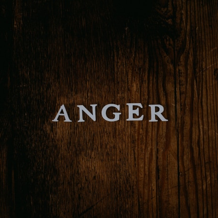 The capital letters for anger laid out on a wooden table