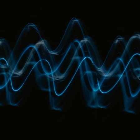 Multiple light beams representing multiple waveforms of sound overlayed on top of each other