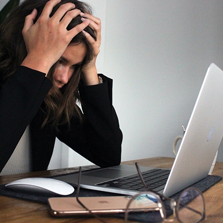 Stressed out woman struggling to deal with distractions on her laptop and smartphone on the table in front of her