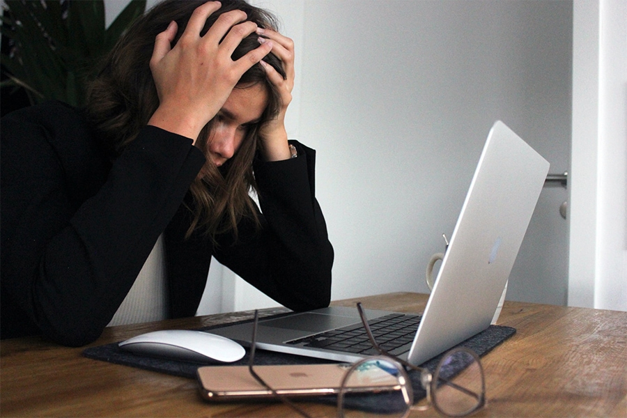 Stressed out woman struggling to deal with distractions on her laptop and smartphone on the table in front of her