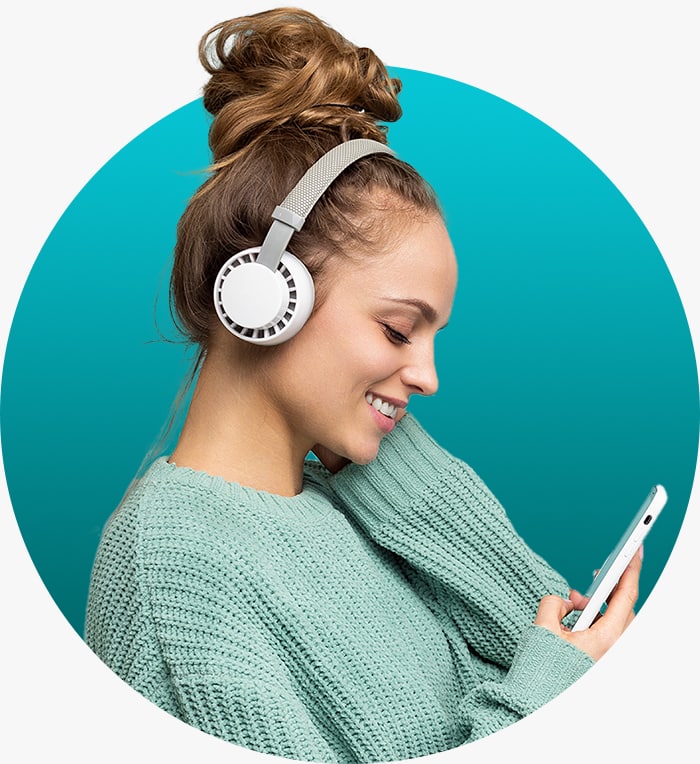 Woman smiles as she listens to a podcast on her smartphone wearing wireless headphones